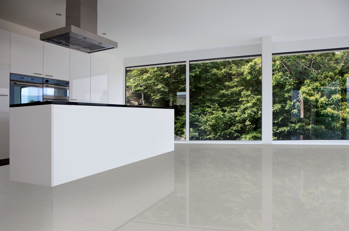 Microcement floors in a minimalist style kitchen equipped with an extractor hood and large windows