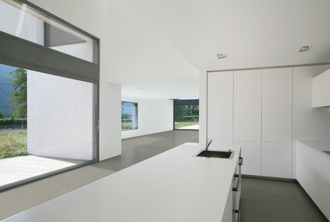 Microcement on the floor of a spacious kitchen with a separate island and views of the garden